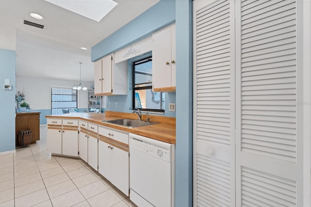 kitchen featuring visible vents, light countertops, white dishwasher, light tile patterned flooring, and a sink