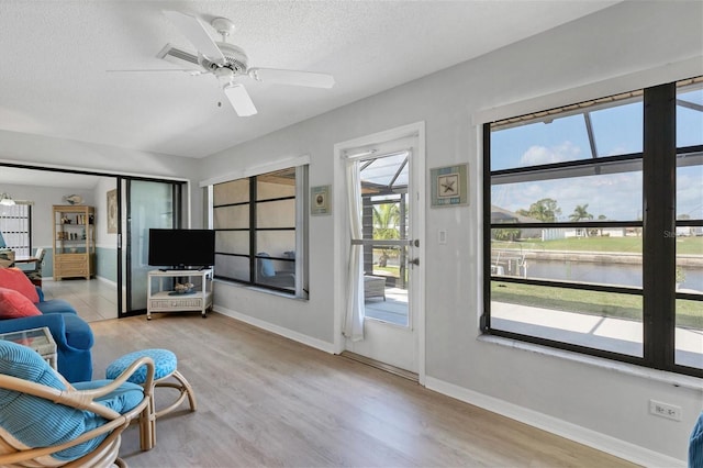 sitting room with ceiling fan, light hardwood / wood-style floors, and a textured ceiling