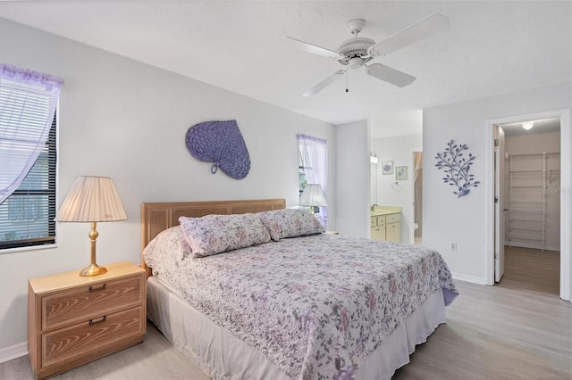 bedroom featuring ensuite bathroom, a walk in closet, ceiling fan, light hardwood / wood-style floors, and a closet