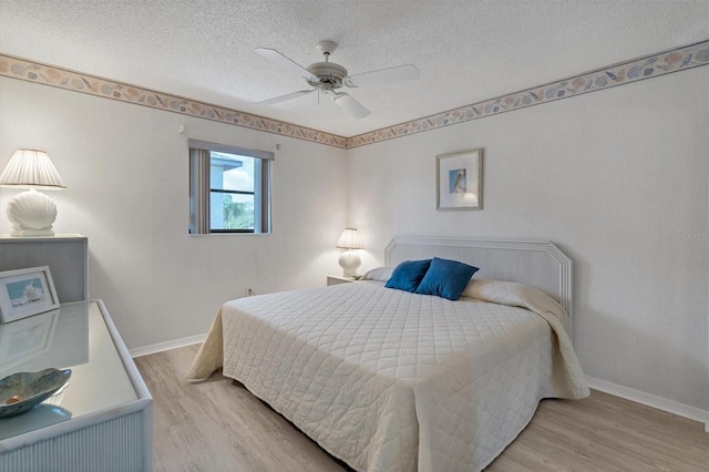 bedroom featuring a ceiling fan, wood finished floors, baseboards, and a textured ceiling