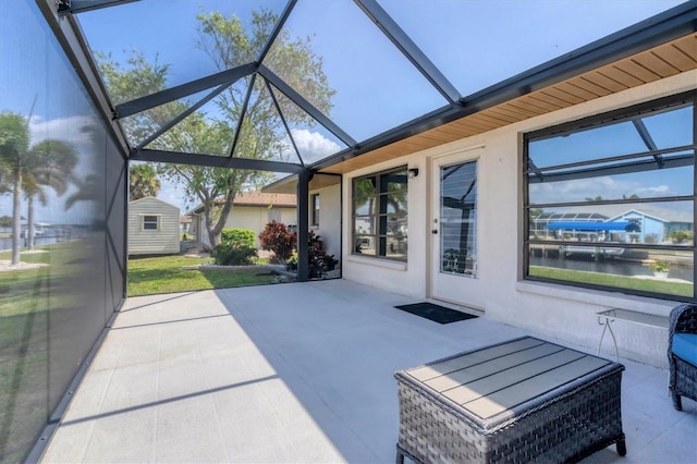 view of patio / terrace with glass enclosure and a water view