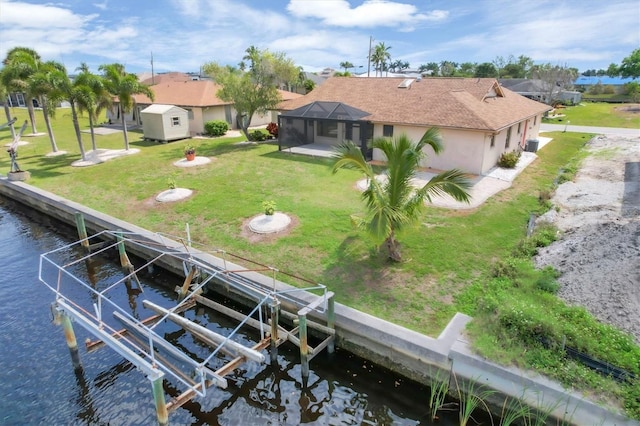 exterior space featuring a water view, a fire pit, a lanai, and a lawn