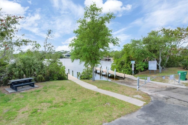 view of dock with a water view and a lawn