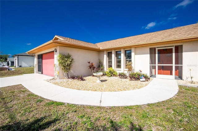 ranch-style home featuring stucco siding, a front lawn, concrete driveway, and a garage