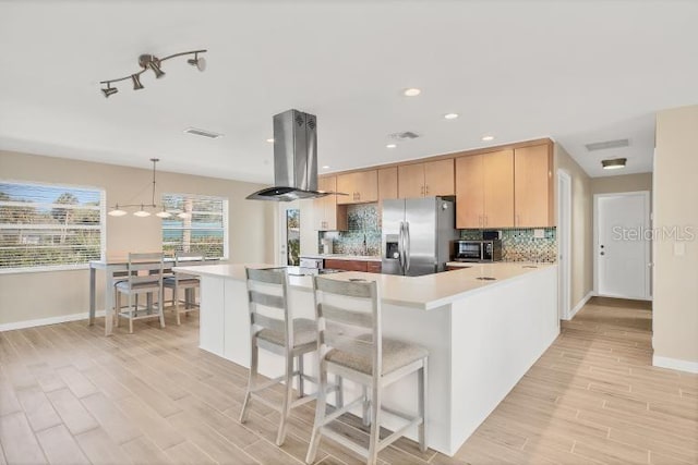 kitchen featuring stainless steel fridge with ice dispenser, light brown cabinets, decorative light fixtures, and island range hood