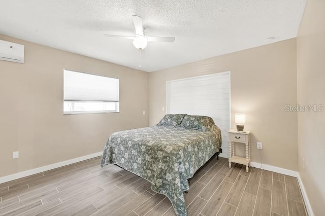 bedroom featuring ceiling fan, a textured ceiling, and a wall unit AC