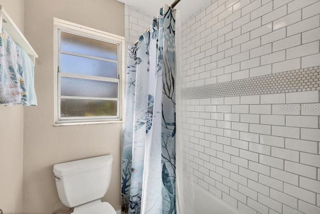 bathroom featuring a wealth of natural light, shower / tub combo, and toilet