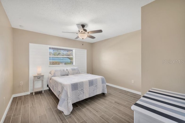 bedroom with a textured ceiling, light wood-type flooring, and ceiling fan