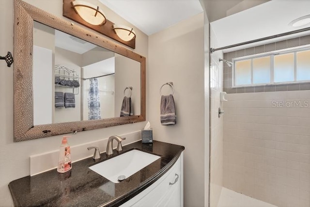 bathroom featuring a tile shower and vanity