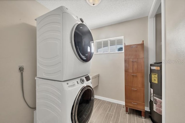 laundry room featuring stacked washer / dryer, water heater, and a textured ceiling