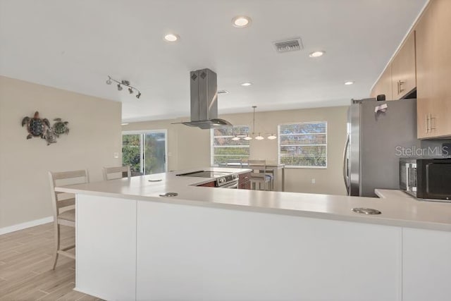 1493 Janet Pl, Englewood, FL 34223 - kitchen with stainless steel appliances, island range hood, light wood-style flooring, light countertops, and a breakfast bar