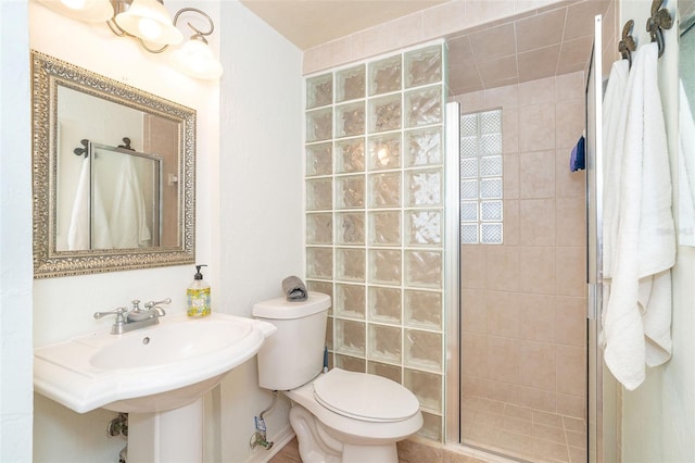 bathroom featuring toilet, a shower with shower door, and sink