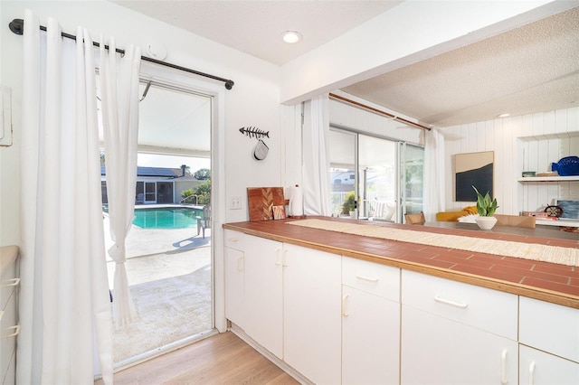 kitchen with white cabinets, light hardwood / wood-style floors, and a textured ceiling