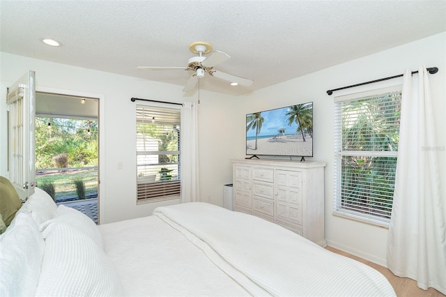 bedroom with ceiling fan, access to exterior, a textured ceiling, and multiple windows