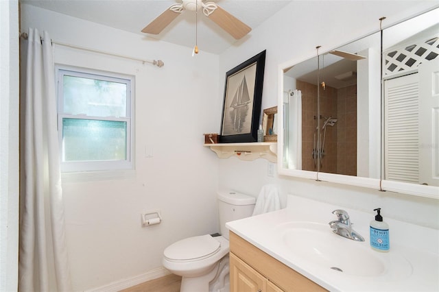 bathroom with a tile shower, vanity, toilet, and ceiling fan