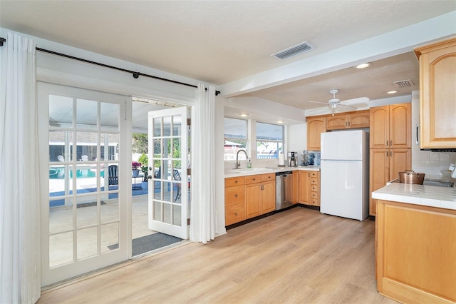 kitchen featuring tasteful backsplash, visible vents, light wood-style flooring, freestanding refrigerator, and stainless steel dishwasher