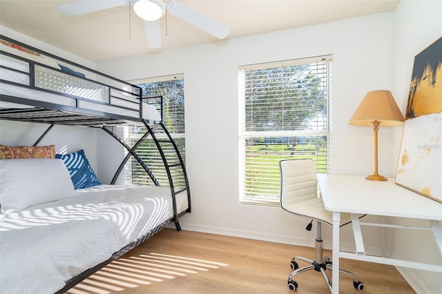 bedroom featuring multiple windows, wood finished floors, and baseboards