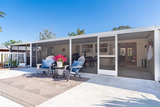 exterior space featuring a sunroom, a patio area, and stucco siding