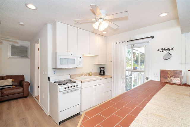 kitchen with light countertops, white cabinets, a sink, a textured ceiling, and white appliances