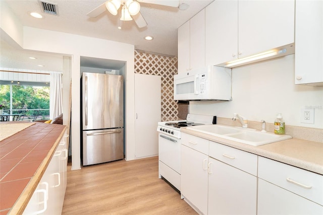 kitchen featuring visible vents, white appliances, a sink, and white cabinetry