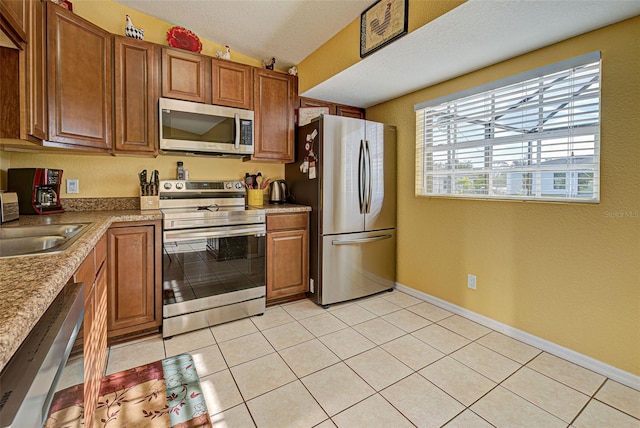 kitchen featuring sink, light tile patterned floors, stainless steel appliances, and vaulted ceiling