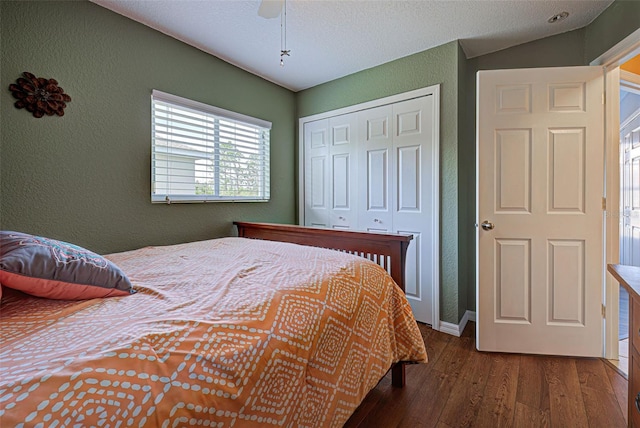 bedroom with dark hardwood / wood-style floors, vaulted ceiling, a closet, and ceiling fan