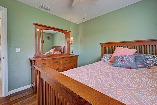 bedroom with a textured ceiling, ceiling fan, and dark wood-type flooring