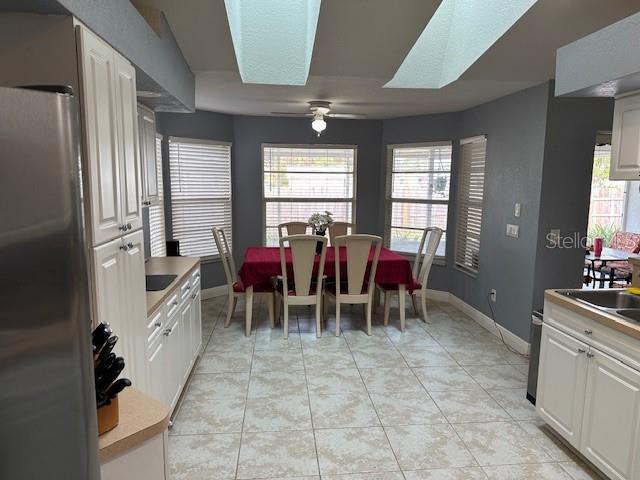 tiled dining room with a skylight and ceiling fan