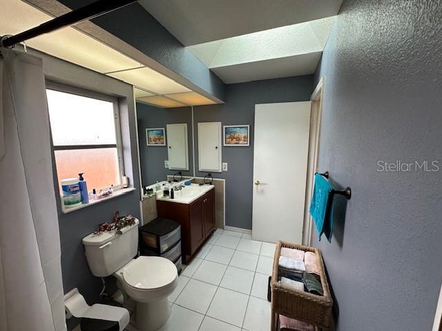 bathroom with tile patterned flooring, vanity, toilet, and walk in shower