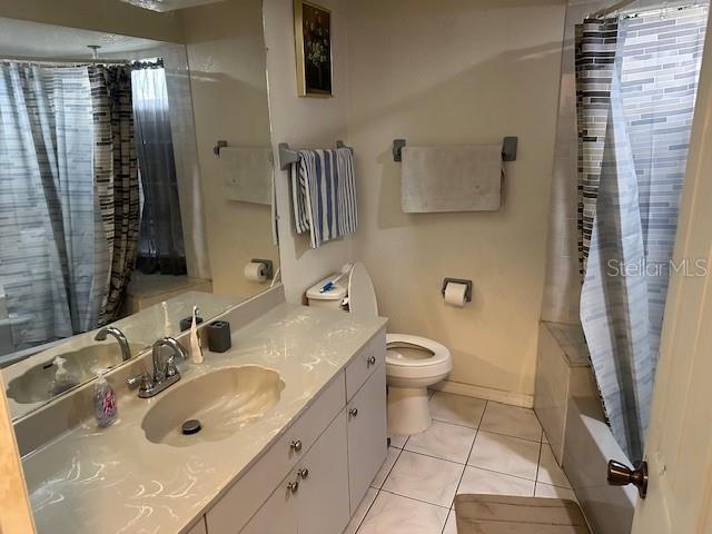 full bathroom featuring tile patterned flooring, shower / bath combo, vanity, and toilet