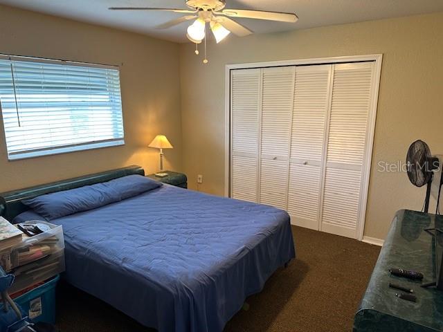 carpeted bedroom with ceiling fan and a closet