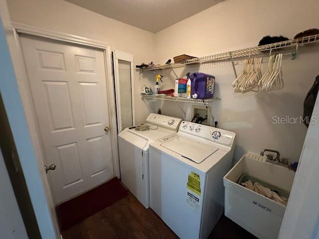 clothes washing area featuring separate washer and dryer, dark hardwood / wood-style floors, and sink