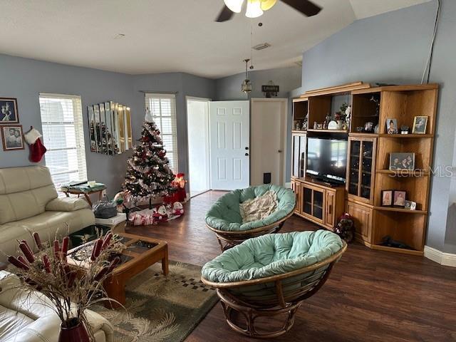 living room with lofted ceiling, ceiling fan, and dark wood-type flooring