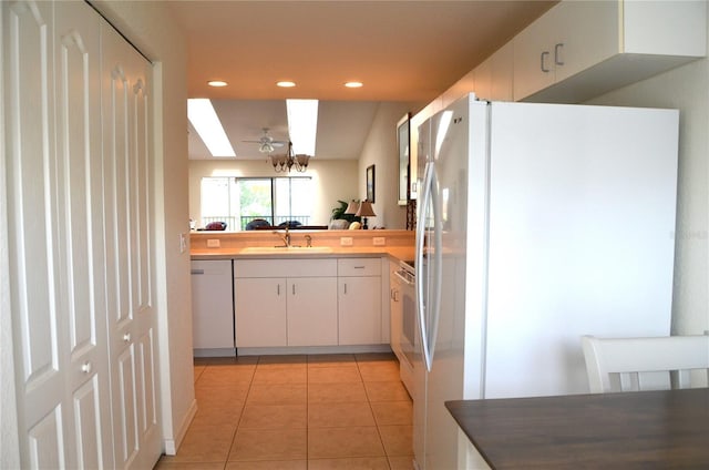 kitchen featuring sink, light tile patterned floors, white refrigerator, dishwasher, and white cabinetry