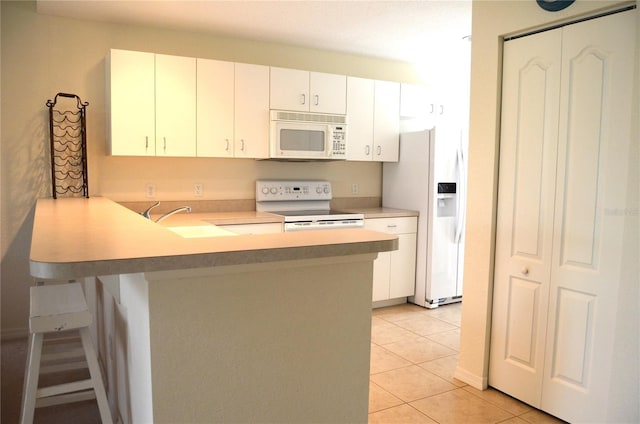 kitchen with kitchen peninsula, light tile patterned floors, white appliances, and white cabinets