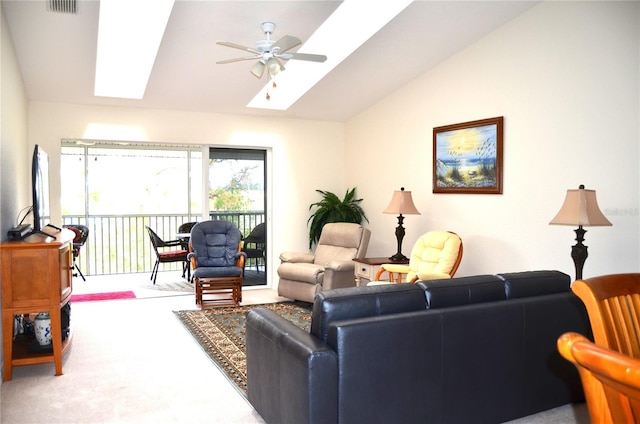 living room with carpet, ceiling fan, and vaulted ceiling with skylight