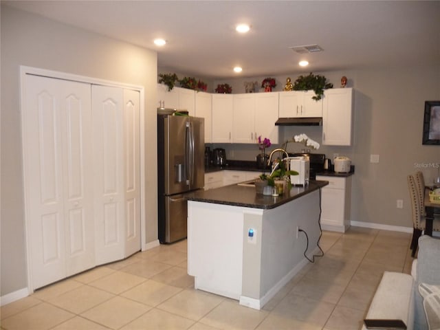 kitchen featuring a kitchen island with sink, sink, stainless steel fridge with ice dispenser, light tile patterned floors, and white cabinetry