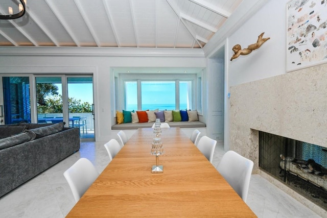 dining space featuring vaulted ceiling with beams and a high end fireplace