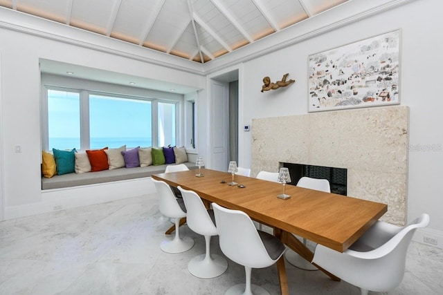 dining area with lofted ceiling with beams and a premium fireplace