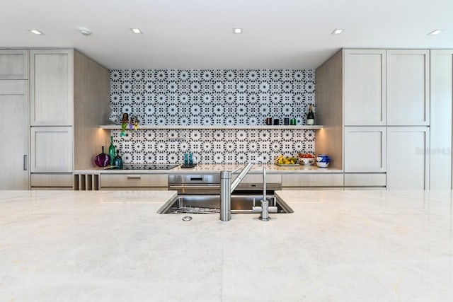 bar featuring light stone countertops, black electric cooktop, tasteful backsplash, and sink