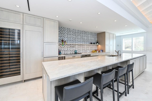 kitchen with a large island, gray cabinetry, decorative backsplash, light stone countertops, and sink