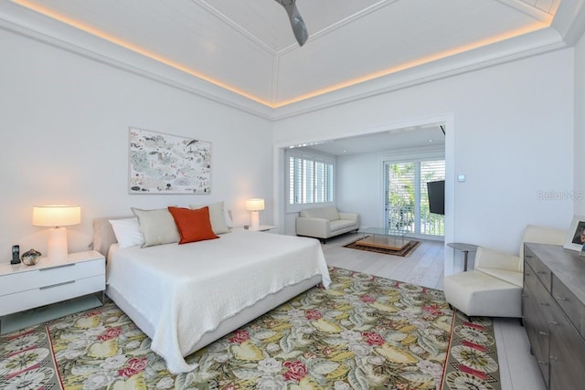 bedroom featuring ceiling fan, crown molding, light hardwood / wood-style flooring, and a raised ceiling