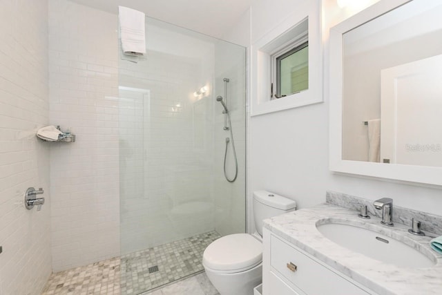 bathroom featuring toilet, vanity, and a tile shower