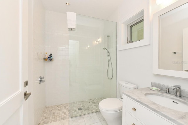 bathroom featuring toilet, tiled shower, and vanity