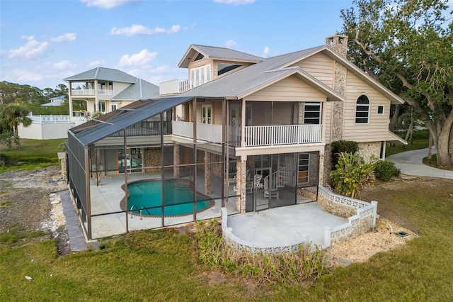 back of property featuring glass enclosure, a patio area, a yard, and a balcony