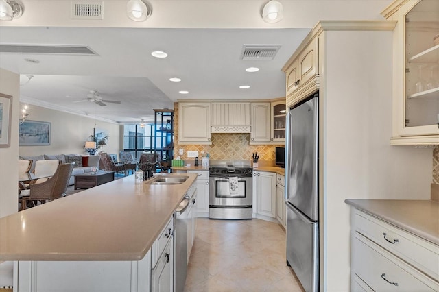 kitchen with appliances with stainless steel finishes, ceiling fan, crown molding, sink, and cream cabinets