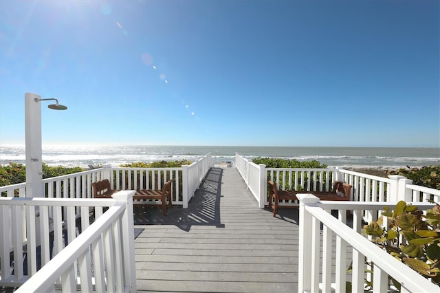 surrounding community with a deck with water view and a view of the beach