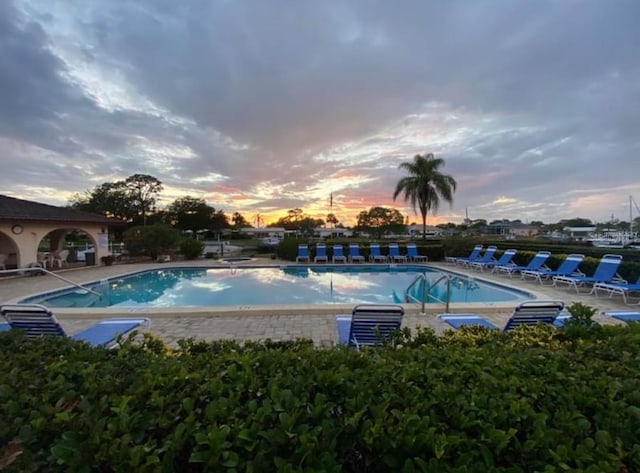 pool at dusk featuring a patio