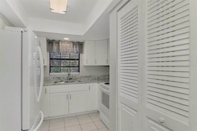 kitchen featuring electric range oven, sink, white refrigerator, white cabinetry, and light tile patterned flooring