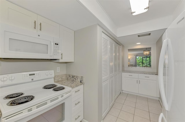 kitchen with light tile patterned floors, white appliances, light stone counters, and white cabinets